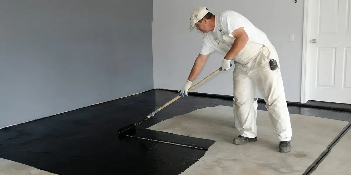 basement waterproofing professional applying waterproof coating to protect a basement floor in Atlanta, GA